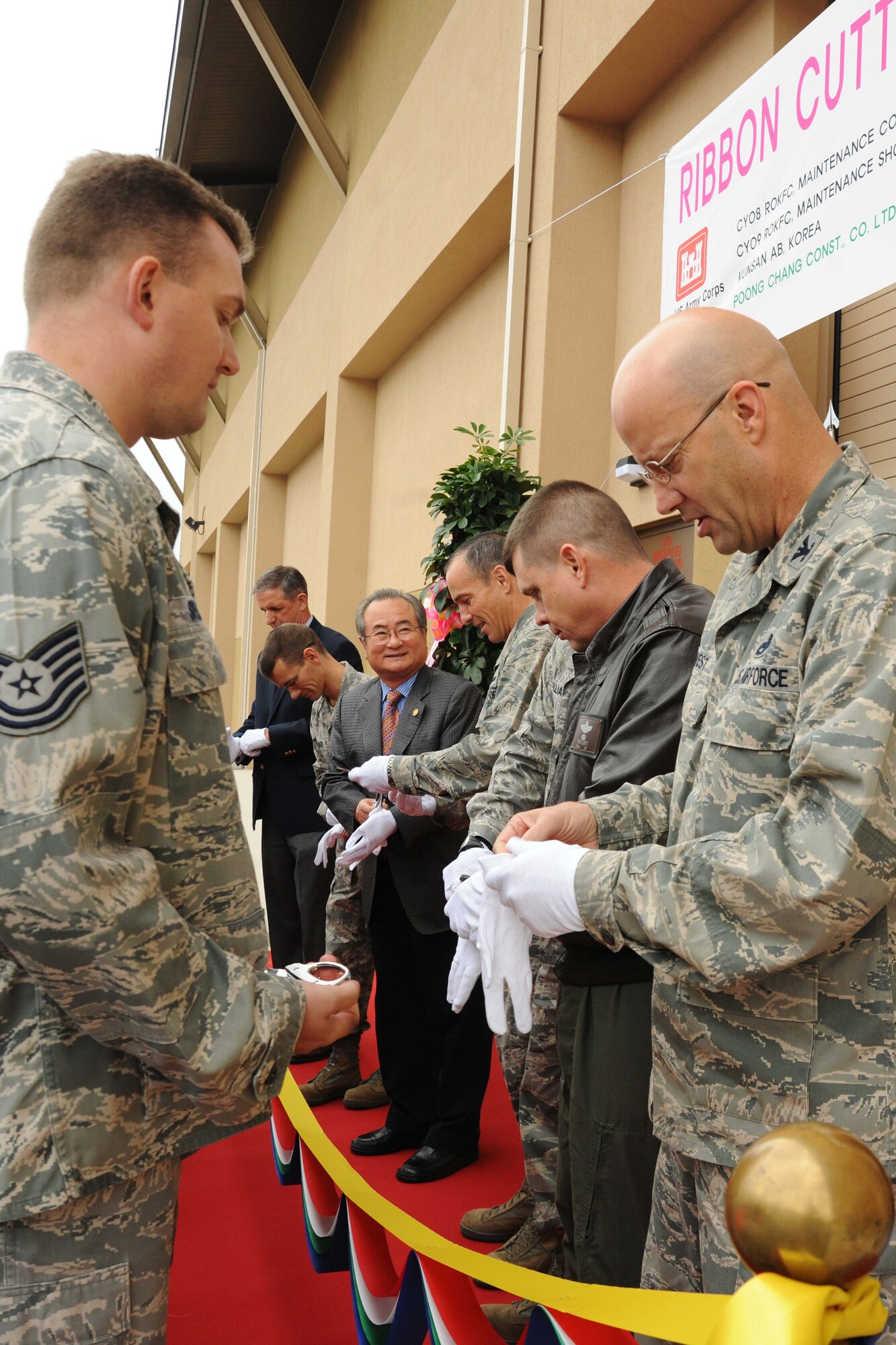 8th Fighter Wing leadership, Samuel Atkins, Far East District United States Army Corps of Engineers, and Imjoo Kim, Poong Chang Construction Company vice president, prepare to cut the ribbon during a ceremony for the opening of a new maintenance complex at Kunsan Air Base, Republic of Korea, Nov. 9. A ribbon cutting ceremony is a traditional ceremony in many cultures that celebrates the final day of construction for a building or other projects. (U.S. Air Force photo by Senior Airman Brittany Y. Auld/Released)