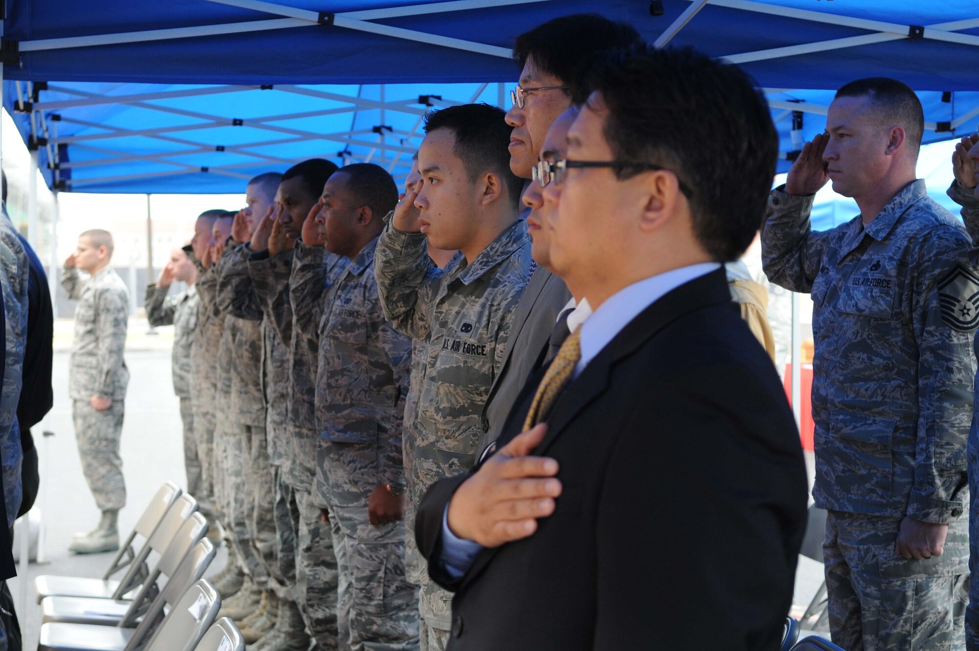Members of the Wolf Pack salute for the playing of the American and Korean National Anthems during the ribbon cutting ceremony for the opening of a new maintenance complex at Kunsan Air Base, Republic of Korea, Nov. 9. A ribbon cutting ceremony is a traditional ceremony in many cultures that celebrates the final day of construction for a building or other projects. (U.S. Air Force photo by Senior Airman Brittany Y. Auld/Released)