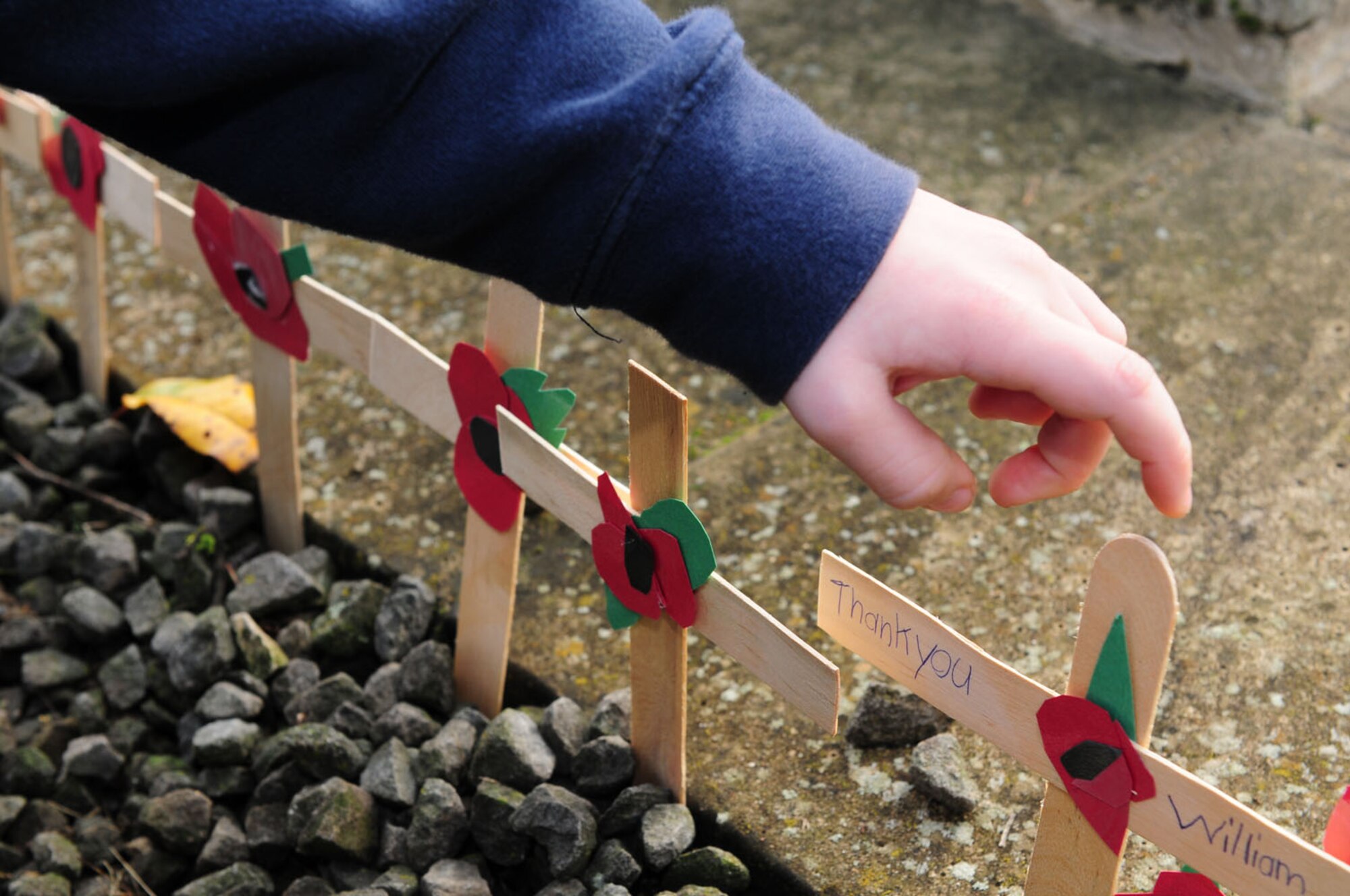 BECK ROW, England -- William Ellis, 7, makes sure his homemade cross and poppy is securely in the ground after he and other children from the RAF Mildenhall Youth Center laid the crosses and a homemade wreath at the war memorial in Beck Row Nov. 10, 2011. Children from Department of Defense Dependents Schools at RAFs Lakenheath and Feltwell made the remembrance decorations and laid them at the local memorial to honor those who have died in wars past and present. (U.S. Air Force photo/Karen Abeyasekere)