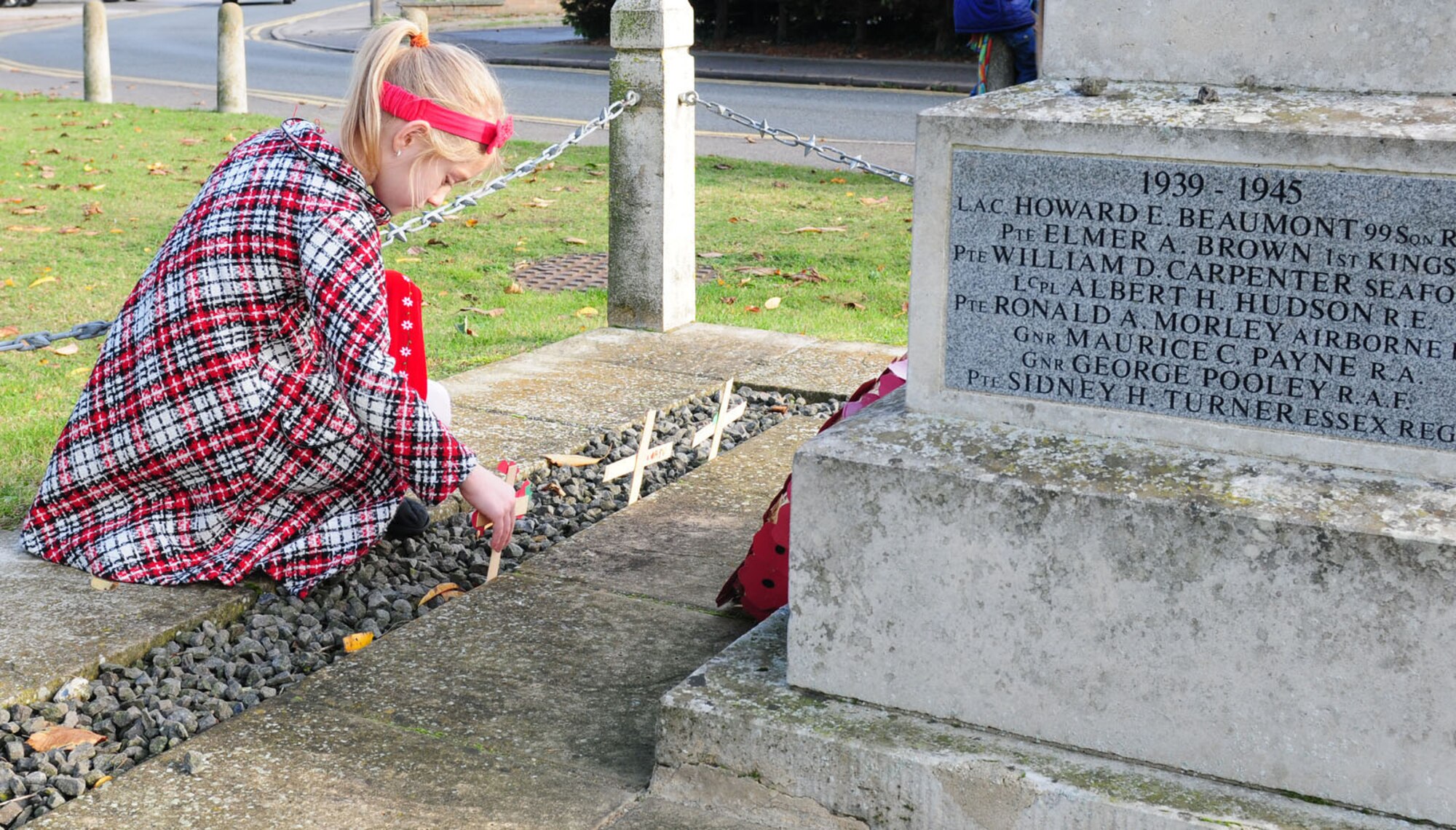 BECK ROW, England -- Olivia Clouse, 7, places a cross and poppy at the war memorial in Beck Row Nov. 10, 2011, in honor of veterans who have lost their lives in past and present wars. Children from the RAF Mildenhall Youth Center, who attend RAFs Lakenheath and Feltwell Department of Defense Dependents Schools, made the crosses and poppies, as well as a cardboard and paper poppy wreath, which they laid at the memorial near RAF Mildenhall. Nov. 11 is Armistice Day -- also known as Remembrance Day -- in the United Kingdom, and Veterans' Day in the United States. (U.S. Air Force photo/Karen Abeyasekere)