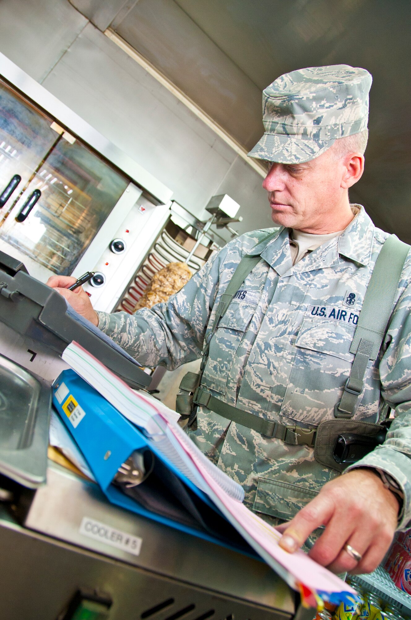 KANDAHAR AIRFIELD, Afghanistan -- Master Sgt. John Kortes, 451st Air Expeditionary Wing Public Health inspector, writes down his findings on a monthly inspection form during inspection at Kandahar Airfield’s boardwalk Nov. 14, 2011. Kortes inspects nearly 20 food facilities at the boardwalk to ensure the safety of the service members, civilians and contractors here. (U.S. Air Force photo by Senior Airman David Carbajal)
