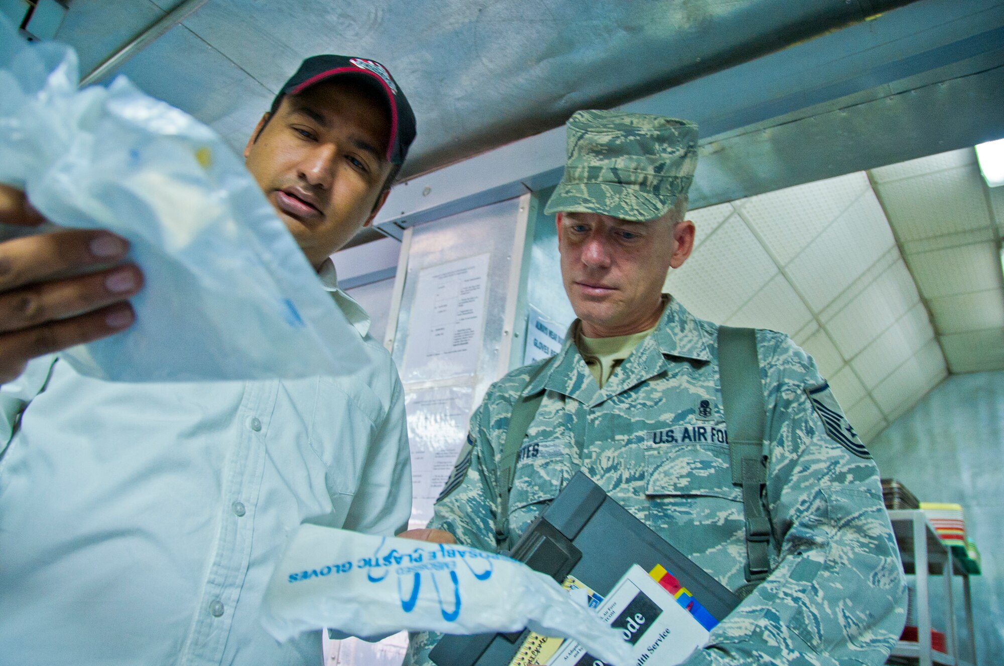 KANDAHAR AIRFIELD, Afghanistan -- Master Sgt. John Kortes, 451st Air Expeditionary Wing Public Health inspector, speaks to a food facility manager about disposable plastic gloves at Kandahar Airfield’s boardwalk Nov. 14, 2011. During formal monthly and informal unannounced inspections, Kortes ensures the food facility workers have sound hand-washing practices and they wear gloves and hats while at the facility. (U.S. Air Force photo by Senior Airman David Carbajal)
