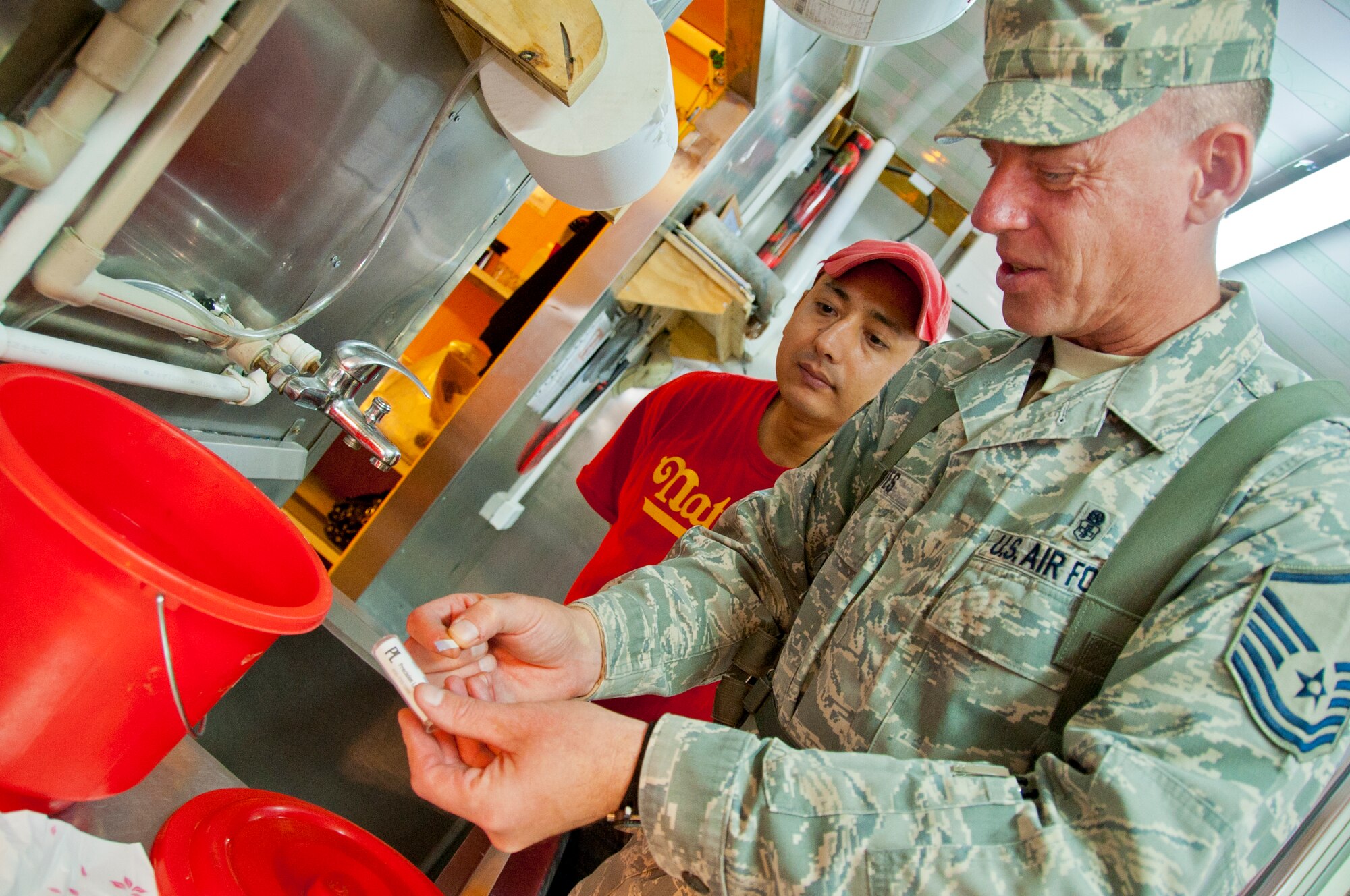 KANDAHAR AIRFIELD, Afghanistan -- Master Sgt. John Kortes, 451st Air Expeditionary Wing Public Health inspector, checks a testing strip after dipping it in the food facility’s sanitizing bucket during a monthly inspection at Kandahar Airfield’s boardwalk Nov. 14, 2011. The testing strips are used to ensure the bucket’s chlorine concentration is high enough to properly sanitize food-contact surfaces. (U.S. Air Force photo by Senior Airman David Carbajal)