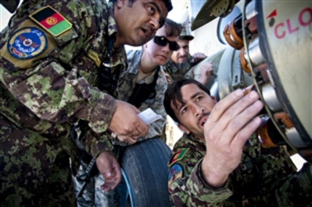 U.S. Air Force Tech. Sgt. Rachel Youkey, center, oversees Afghan airmen as they load the rocket pod of a Mi-17 helicopter with rockets at Kandahar Airfield, Afghanistan, Nov. 13, 2011. Youkey is a munitions air adviser assigned to the 738th Air Expeditionary Advisory Group.