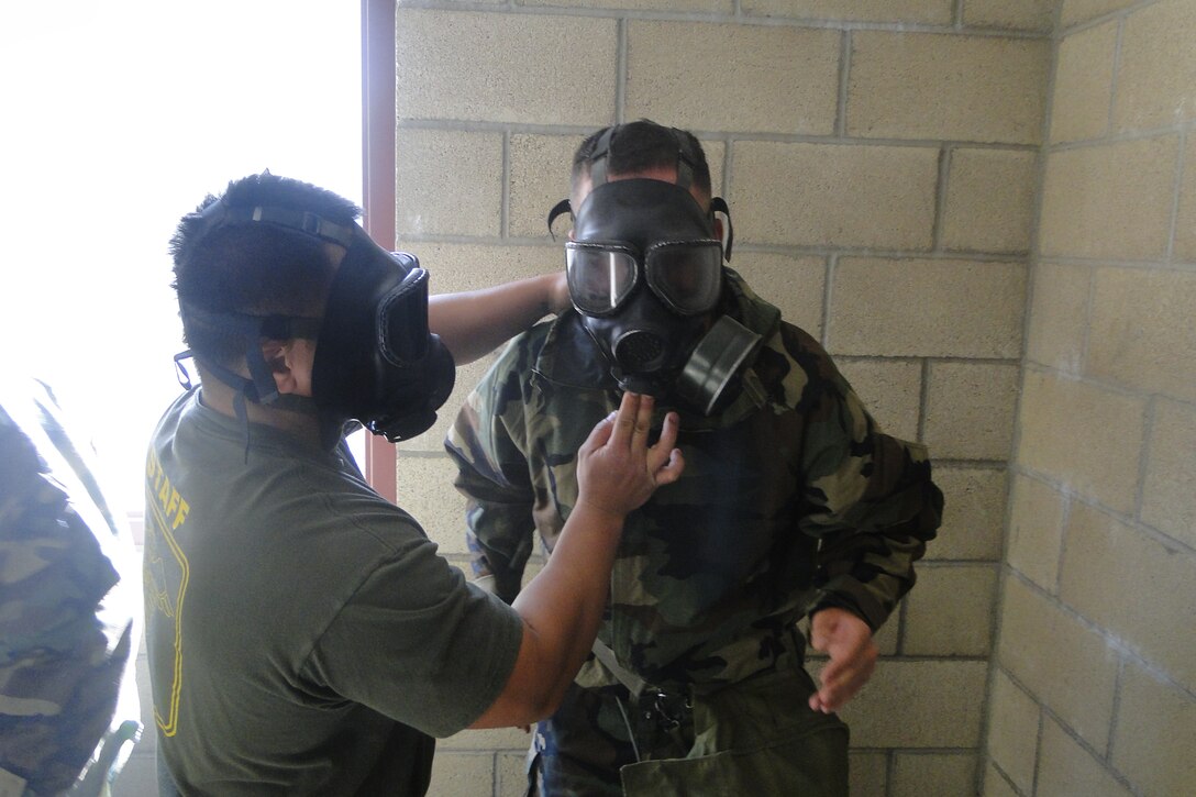 HM2 Salanguit helps a student don and clear his M40 gas mask in the confidence chamber.