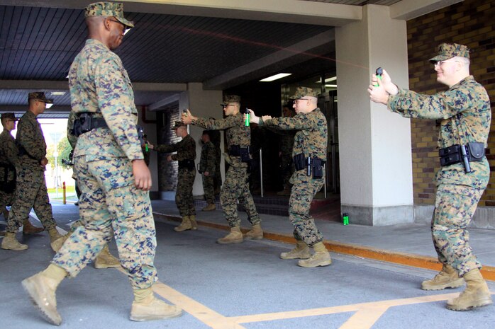 Lance Cpl. James S. Huston, station Provost Marshal’s Office military police officer, uses inert oleoresin capsicum spray on Lance Cpl. Mico B. Young, station PMO military police officer, in a training exercise that took place at an empty mid-rise in the Monzen District here Nov. 15. The inert OC spray allows PMO to practice accuracy without causing the burning sensation of regular OC spray.