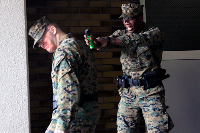 Lance Cpl. Mico B. Young, station Provost Marshal’s Office military police officer, uses inert oleoresin capsicum spray on Lance Cpl. James S. Huston, station PMO military police officer, in a training exercise that took place at an empty mid-rise in the Monzen District here Nov. 15. The inert OC spray allows PMO to practice accuracy without causing the burning sensation of regular OC spray.
