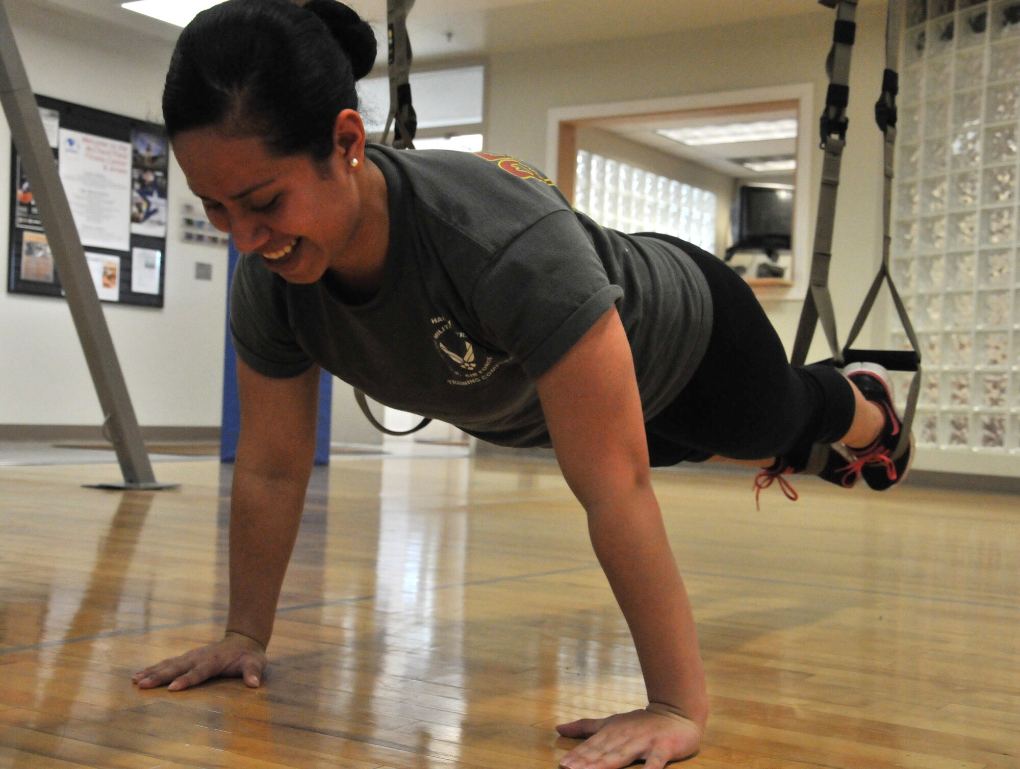 Senior Airman Jocelyn Cervantes, installation readiness advisor with the 446th Force Support Squadron, shows no mercy as she smiles through suspended pushups on the new fitness equipment at the Fitness Annex here Nov. 15, 2011.  Cervantes leads by example early in her Air Force Reserve career by achieving an excellent rating on all of her physical fitness assessments.
