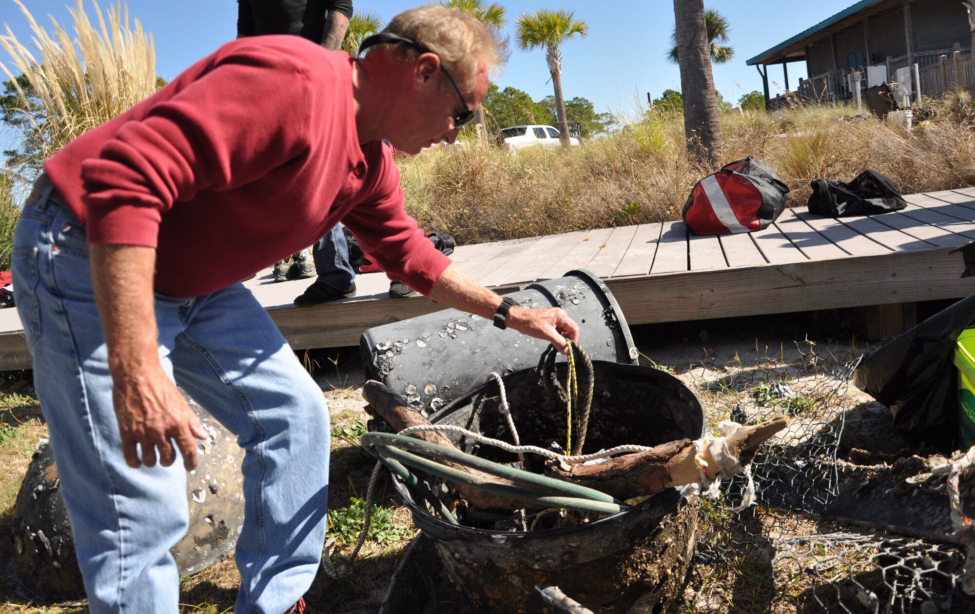 Mike Gray, water operations instructor at Air Force Special Operations Command Special Tactics Training Squadron, Hurlburt Field, Fla., sorts through debris gathered in a cleanup of the Hurlburt Marina Nov. 12, 2011. Items pulled from the water included old carburetors, chain link fence, crab traps and buckets full of cement. Volunteers cleared the waterways of 3,700 pounds of debris.(U.S. Air Force photo/Rachel Arroyo) RELEASED