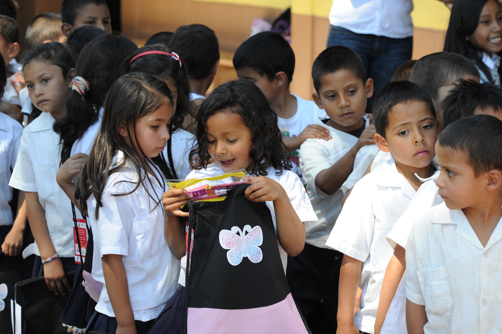Honduran children receive backpacks from volunteers assigned to Soto Cano Air Base, Honduras, Nov. 9, 2011, near Tegucigalpa, Honduras. The volunteers handed out more than 600 backpacks and 30 hygiene kits to needy Honduran children at three schools. (U.S. Air Force photo/Tech. Sgt. Matthew McGovern)