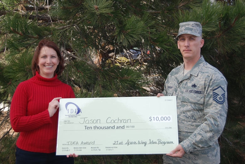 PETERSON AIR FORCE BASE, Colo. -- Jennifer Butcher, 21st Space Wing Innovative Development through Employee Awareness program manager, presents a $10,000 check to Master Sgt. Jason Cochran, Air Force Space Command air transportation manager, for his winning idea. Cochran’s idea will save the Air Force an estimated $3 million in the first year of implementation. (U.S. Air Force photo/Steve Brady)