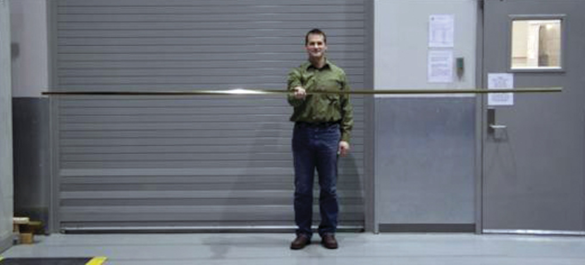 Jeremy Banik, program manager and co-inventor of the TRAC boom, with the slender, 13-foot TRAC mast, fabricated at Kirtland Air Force Base.  (AFRL Image)