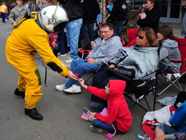 An Airman from the 9th Physiological Support Squadron, Beale AFB, Calif., hands candy to a local youth while wearing a full pressure suit during the Veterans Day Parade in Marysville, Calif., November 11, 2011. Full pressure suits are used while flying the U.S. Air Force U2 Dragon Lady intelligence, surveillance and reconnaissance aircraft. Many units from Beale showcased equipment used at the base. (U.S. Air Force photo by Airman 1st Class Shawn Nickel)