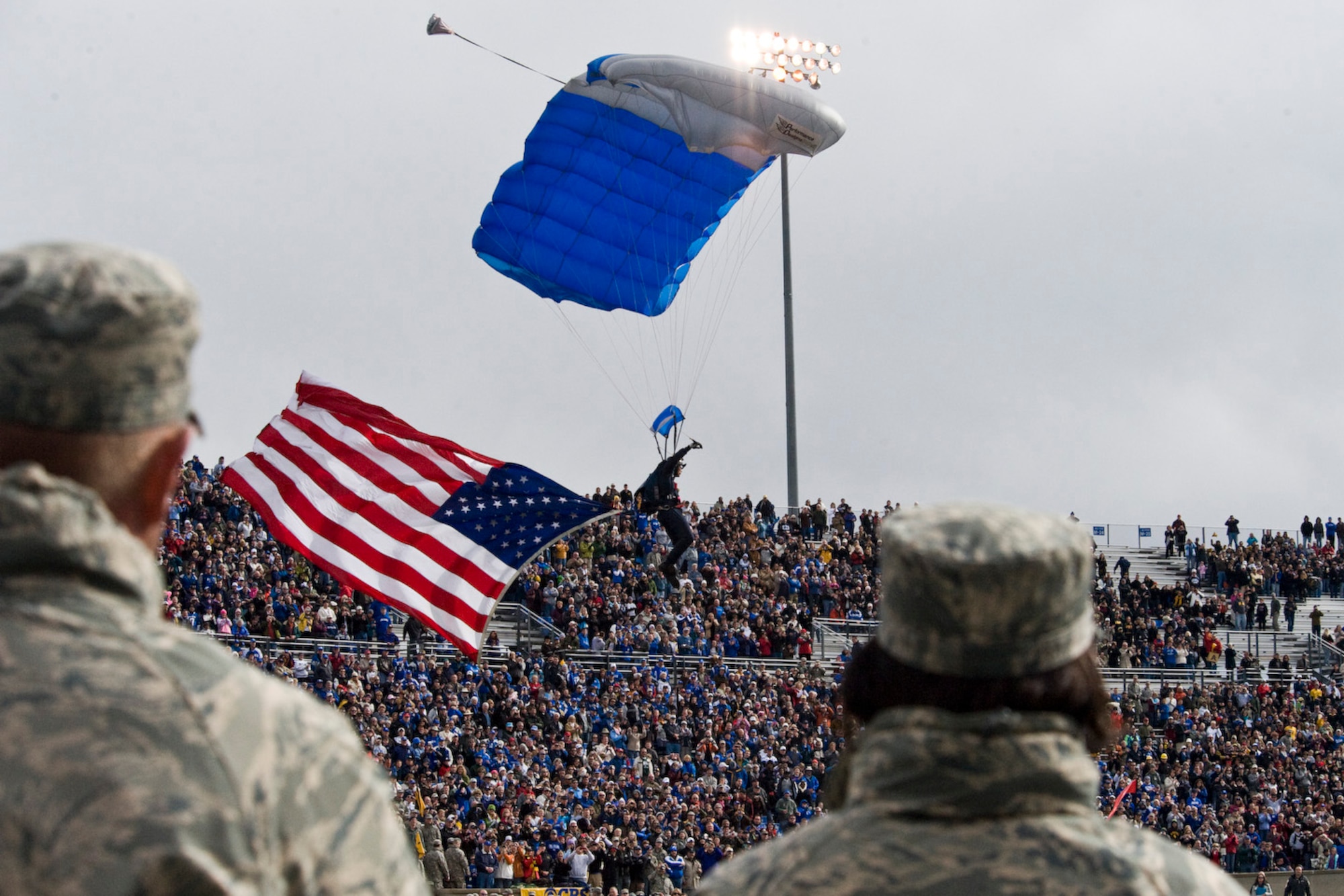 A parachutist glides onto the field before the Air Force Falcons vs. Army Knights football game at the Air Force Academy, Colo., Nov. 5, 2011. The American flag was being carried by one of four jumpers to kick off the football game. (U.S. Air Force photo by Airman Alystria Maurer/Released)
