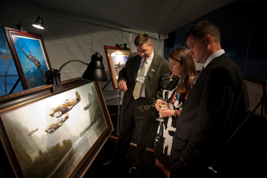 Members of the 2011 Flying Tiger Reunion observe artwork by John Shaw during the 2011 Flying Tigers Reunion dinner in Tampa, Fla., Nov. 12, 2011. Shaw said he had been inspired to create Flying Tiger art since he was a young teen. U.S. Air Force Capt. Timothy Grebs, 75th Fighter Squadron pilot, later won one of Shaw's paintings in a raffle drawing. (U.S. Air Force photo by Staff Sgt. Jamal D. Sutter/Released)