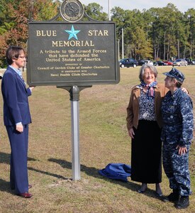 Captain Mary Kim Kenney-Gutshall accepts the Blue Star Memorial Marker from Trish Bender, left, and Betty Gourdin during a dedication of the Blue Star Memorial Marker ceremony at Joint Base Charleston- Weapons Station Nov. 10.  The Blue Star Memorial is a tribute to all men and women who have served, are serving, or will serve in the United States Armed Forces. Kenney-Gutshall is the Naval Health Clinic Charleston commanding officer, Trish Bender is the President of the Council of Garden Clubs of Greater Charleston and Betty Gourdin is the Council of Garden Clubs of Greater Charleston and the Garden Club of South Carolina Blue Star Memorial chairman. (U.S. Navy photo/Petty Officer 3rd Class Brannon Deugan)