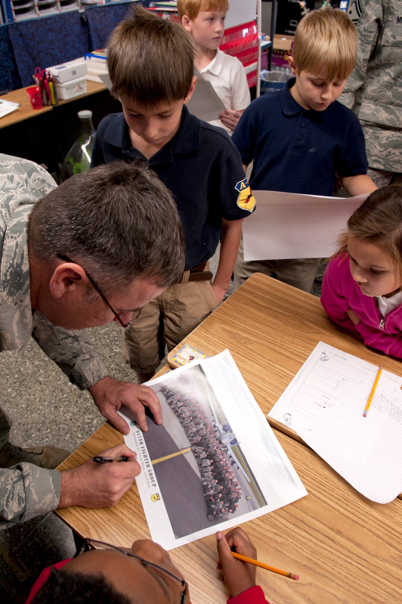 U.S. Air Force Senior Master Sgt. Mike Thornton, 917th Aircraft Maintenance Squadron production superintendent, signs a photo for a group of students at the Phoenix Magnet Elementary School in Alexandria, La., Nov. 10, 2011. The school hosted a group of 917th Fighter Group personnel, who visited all 675 students, answering questions about themselves, their jobs and the Air Force Reserve. (U.S. Air Force photo by Master Sgt. Greg Steele/Released)