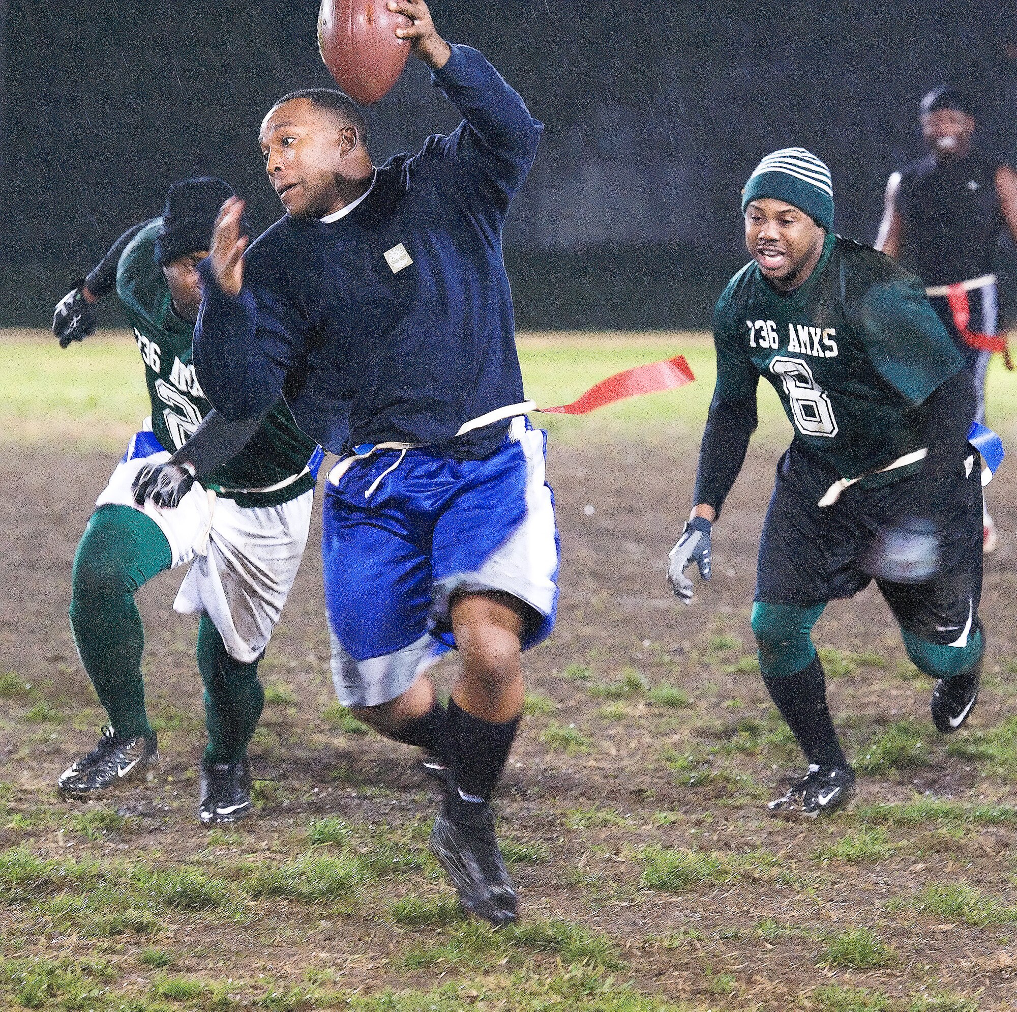 Dennis Proctor, center, tries to evade Andre Leonard, right, and another defender during a flag football game Nov. 10, 2011, at Dover Air Force Base, Del. The 736th Aircraft Maintenance Squadron defeated the 436th Security Forces Squadron with a score of 34-6 in the playoff match. (U.S. Air Force photo by Airman 1st Class Samuel Taylor)

