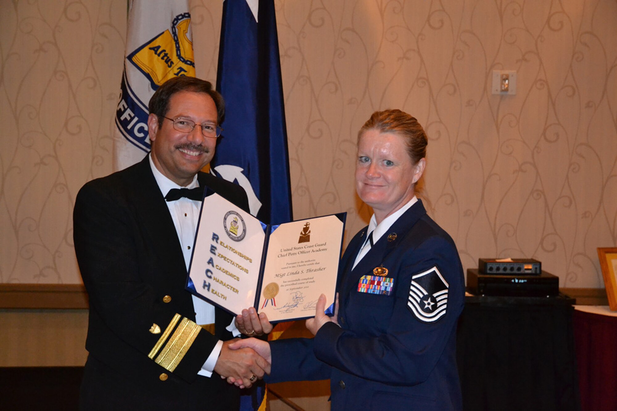 WRIGHT-PATTERSON AIR FORCE BASE, Ohio - Master Sgt. Linda Thrasher, 445th Force Support Squadron, assistant chief of education and training, is congratulated by Rear Admiral Joseph R. Castillo, commander, Coast Guard Eleventh District, after graduating from the U.S. Coast Guard Chief Petty Officer Academy Sept. 16. The five-week course held in Pentaluma, Calif., had approximately 70 students divided into smaller teams and included topics on professionalism, self-awareness, leadership, communications, and strategic thinking. (Courtesy photo)