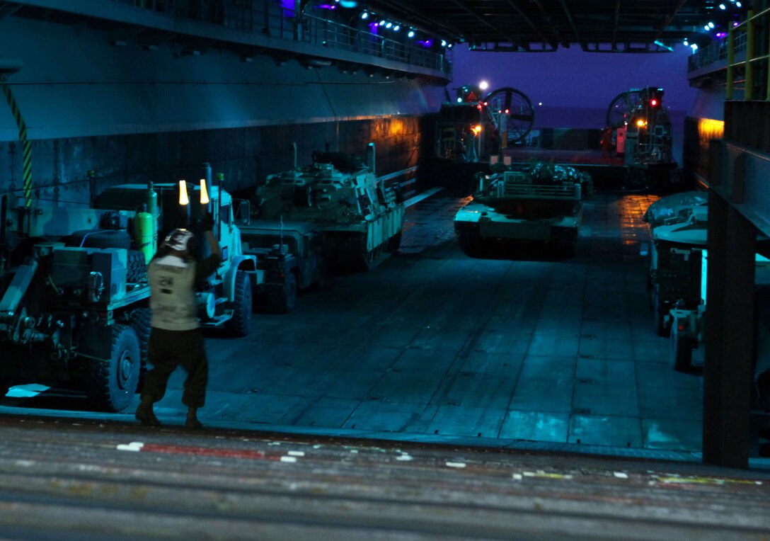 Cpl. Robert R. Jones directs a tank with Battalion Landing Team 3/1, 11th Marine Expeditionary Unit, in the well deck Nov. 14. The battalion is the ground combat element for the unit, which embarked USS Makin Island, USS New Orleans and USS Pearl Harbor in San Diego and began its seven-month deployment to the Western Pacific and Middle East regions. Jones, an 11th MEU combat cargo Marine, is a 24-year-old Toledo,Ohio, native.