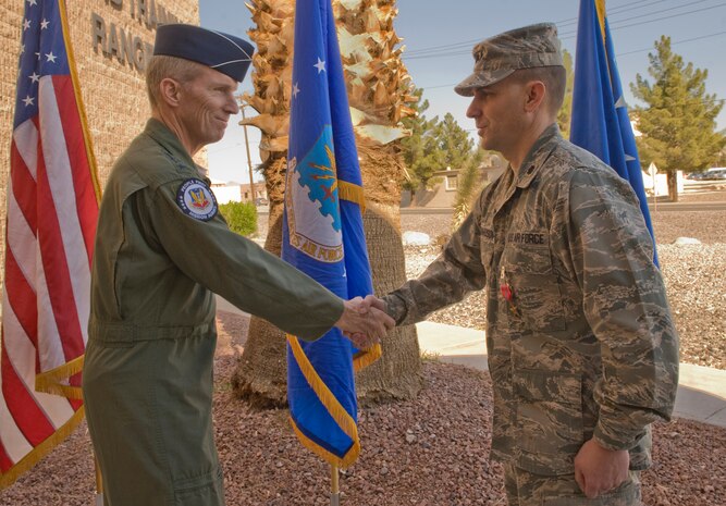 U.S. Air Force Gen. Mike Hostage, Air Combat Command commander, shakes hands with U.S. Air Force Lt. Col. Thomas Richardson, Nevada Test and Training Range chief of staff, during a Bronze Star Medal presentation Nov. 8, 2011, at Nellis Air Force Base, Nev.  Richardson was awarded the Bronze Star for executing countless missions and flying hours as a commander and signals intelligence officer in support of Operation Enduring Freedom and Operation New Dawn September 22, 2010, to March 30, 2011.  (U.S Air Force photo by Senior Airman Stephanie Rubi / Released)