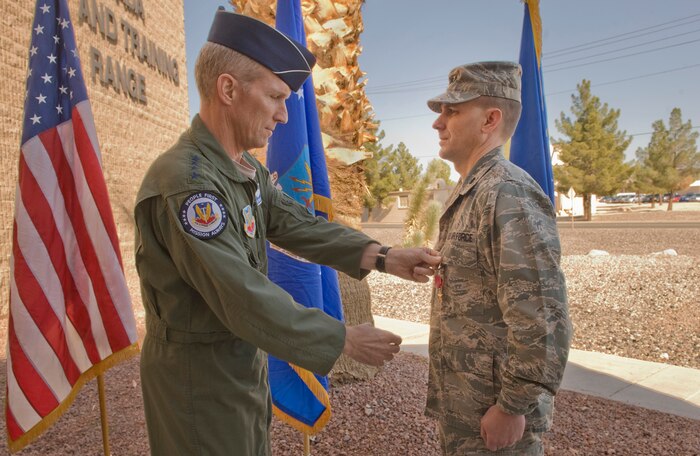U.S. Air Force Gen. Mike Hostage, Air Combat Command commander, pins on the Bronze Star to  U.S. Air Force Lt. Col. Thomas Richardson, Nevada Test and Training Range chief of staff, Nov. 8, 2011, at Nellis Air Force Base, Nev. Richardson was awarded the Bronze Star for executing countless missions and flying hours as a commander and signals intelligence officer in support of Operation Enduring Freedom and Operation New Dawn September 22, 2010, to March 30, 2011.  (U.S Air Force photo by Senior Airman Stephanie Rubi / Released)