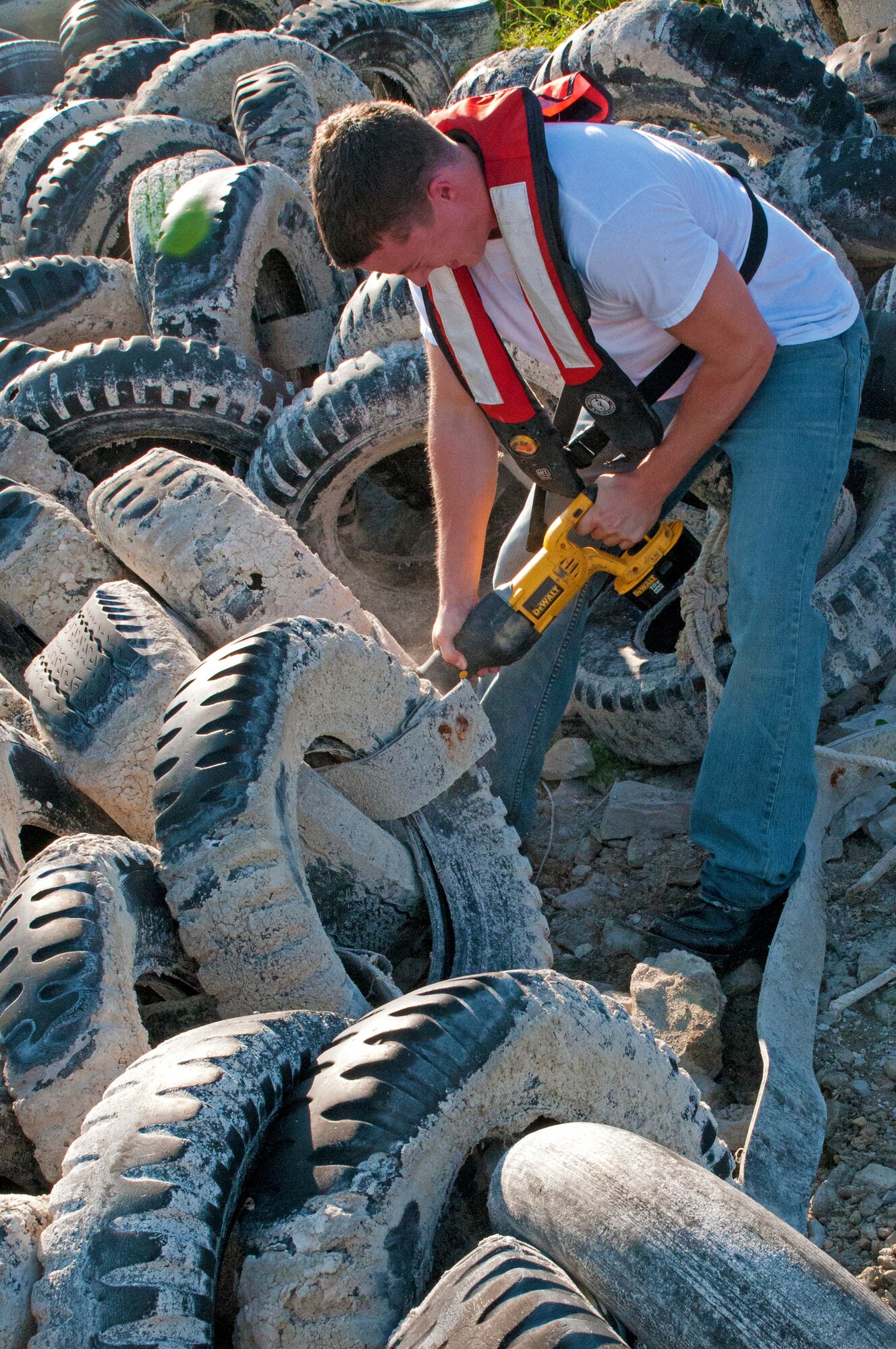 LAUGHLIN AIR FORCE BASE, Texas – 2nd Lt. Justin Hitchens, 47th Operations Support Squadron, saws through a strap holding a dozen beached tires together at Lake Amistad Sept. 2.The old WWII Jeep tires were installed in the marina decades ago by the Army Corps of Engineers to protect the marina from high winds. Powerful storms throughout the last 30 years damaged the structure and ultimately gave way in 2011, littering the shorelines. (U.S. Air Force photo/Senior Airman Scott Saldukas)