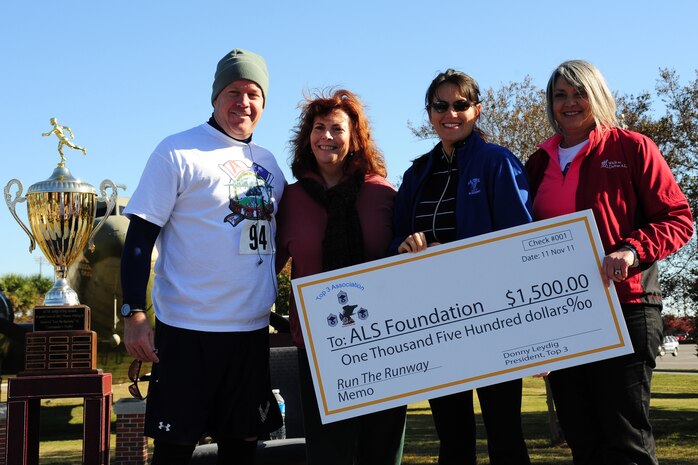 Col. Erik Hansen, Carmen Mikolajcik, Julia Mikolajcik-Vanderpool and Rebecca Jordan pose with a check for $1500 that was raised to support the Amyotrophic Lateral Sclerosis Foundation. This event completed the third annual Run the Runway 5k honoring Brig. Gen. (Ret.) Thomas Mikolajcik Nov. 11, on Joint Base Charleston - Airbase, S.C. A combination of Team Charleston personnel and local civilians participated in the run. Hansen is the 437th Airlift Wing commander, Carmen is the surviving spouse and Julia is the daughter of Brig. Gen. (Ret.) Mikolajcik and Rebecca is an ALS representative (U.S. Air Force photo/Tech Sgt. Chrissy Best) 