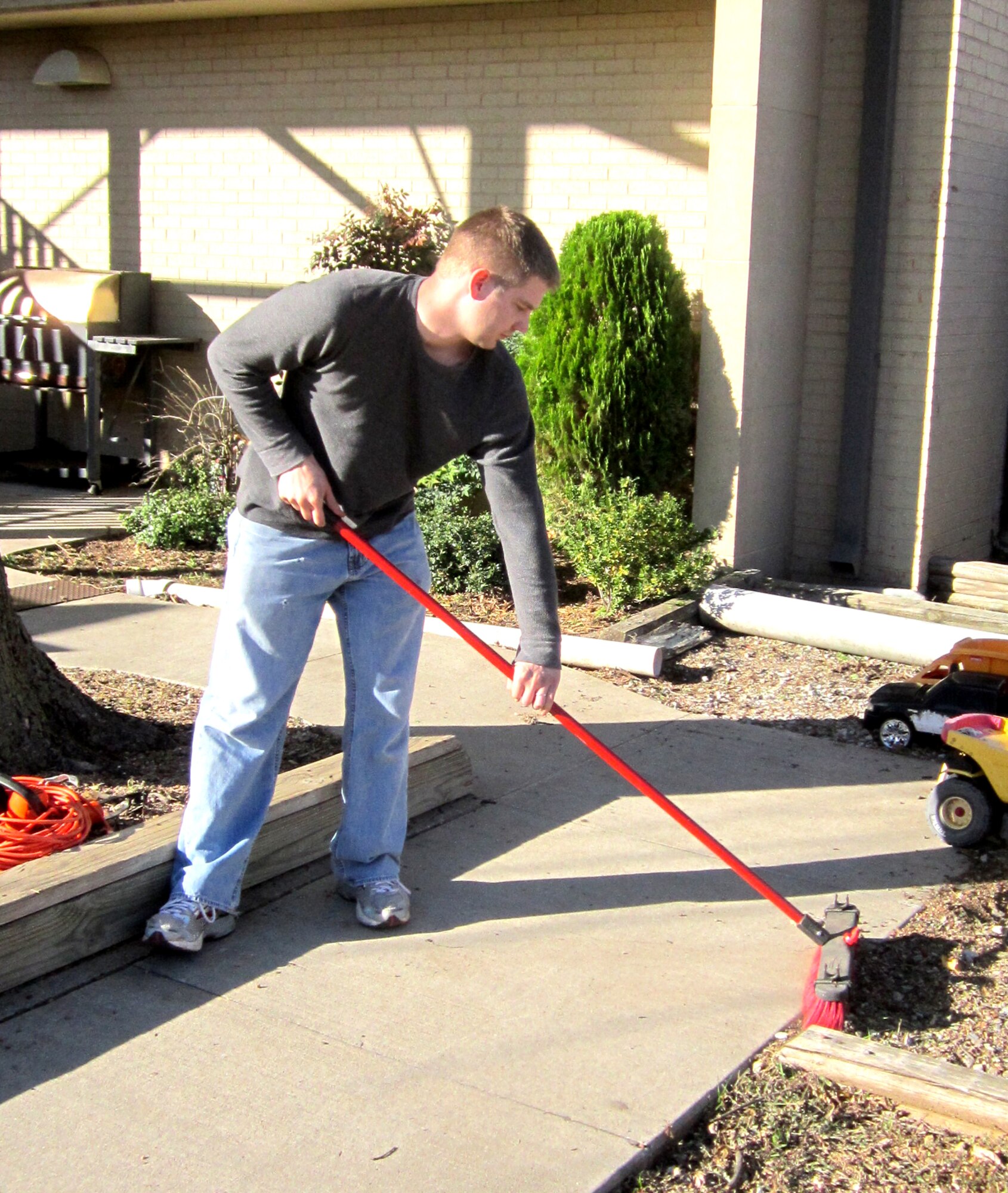 Senior Airman Thomas Valeich with the 71st Operations Support Squadron radar approach control, at Vance Air Force Base, Okla., sweeps off sidewalks while volunteering at the YWCA in Enid, Okla., Nov. 12. (Courtesy photo) 