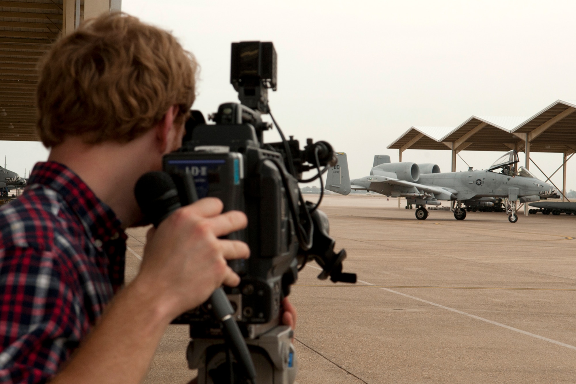 Paul Sweazy, KTAL Channel 6 photojournalist, records video of a 47th Fighter Squadron A-10 Thunderbolt II as it taxis to its parking after returning from a Green Flag mission, Barksdale Air Force Base, La., Nov. 15, 2011. Sweazy recorded flight line video and interviews for a weekly Barksdale Profile segment which highlights events happening on base. (U.S. Air Force photo by Master Sgt. Greg Steele/Released)