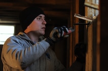 MINOT, N.D. -- Staff Sgt. Jacob Udell, 91st Missile Security Forces Squadron response force leader, sets a window in place with cement here Nov. 9. On-and-off duty, Udell helps his Airmen prepare their homes for the fast approaching winter months. Due to this summer’s flood situation, affected Minot residents are rushing to rebuild their homes. (U.S. Air Force photo/Senior Airman Ashley N. Avecilla)