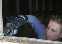 MINOT, N.D. -- Staff Sgt. Jacob Udell, 91st Missile Security Forces Squadron response force leader, sets a window in place with cement here Nov. 9. On-and-off duty, Udell helps his Airmen prepare their homes for the fast approaching winter months. Due to this summer’s flood situation, affected Minot residents are rushing to rebuild their homes. (U.S. Air Force photo/Senior Airman Ashley N. Avecilla)