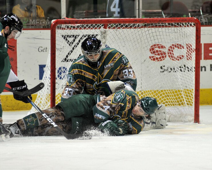 Sioux City Musketeer defenseman Geoff Ferguson slides  on the ice to block  the puck as Austin Priebe, the goalie, watches during the annual veterans  appreciation game held at the Tyson events center in Sioux City, Iowa.   The Musketeers celebrate the annual Veterans Day game with special uniforms and free tickets to all the area veterans.  As an added bonus this year the Musketeers defeated the Tri-City Storm 6-3.  USAF photo by MSgt. Bill Wiseman (Released)