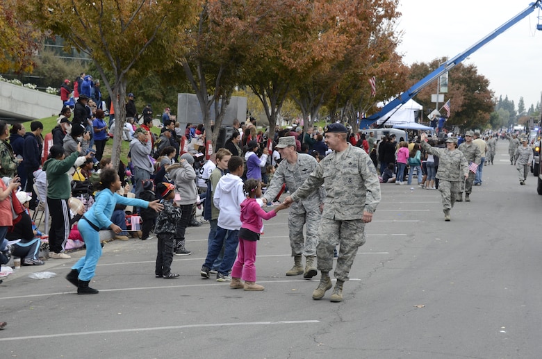 U.S. Air Force Colonel Clay Garrison, 144th Fighter Wing Vice Commander, and Chief Master Sergeant James Layne, 144th Security Forces Squadron Superintendent, shake hands with several children watching the 92nd Fresno Veterans Day Parade.  The parade is considered the largest event of its kind west of the Mississippi with over 9,000 volunteers and participants.  (U.S. air Force photo by SMSgt. Chris Drudge)