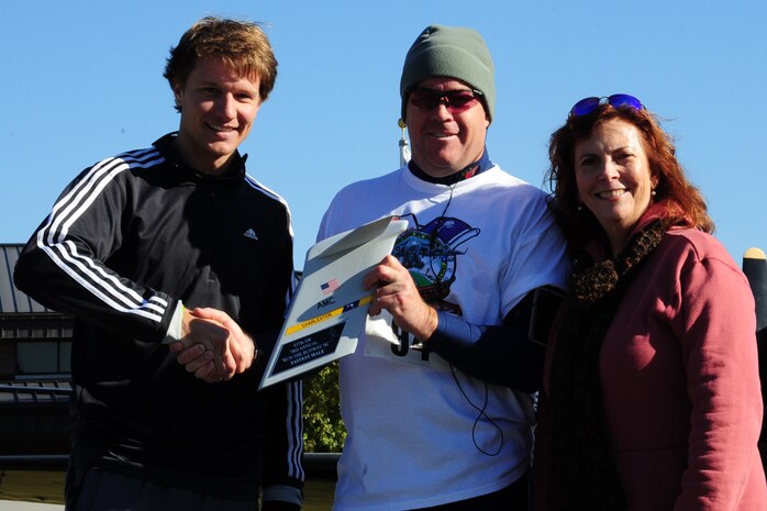Col. Erik Hansen and Carmen Mikolajcik present Nate Bergeron from Charleston, the "Top Males Overall" award with a time of 17:36 after running the  third annual Run the Runway 5K event honoring Brig. Gen. Thomas Mikolajcik Nov. 11 at Joint Base Charleston - Air Base.  The 5k course took place on JB Charleston's runway.  The event was held to raise awareness of Amyotrophic Lateral Sclerosis.  Hansen is the 437th Airlift Wing commander and Carmen is the surviving spouse of Mikolajcik. (U.S. Air Force photo/Tech. Sgt. Chrissy Best) 