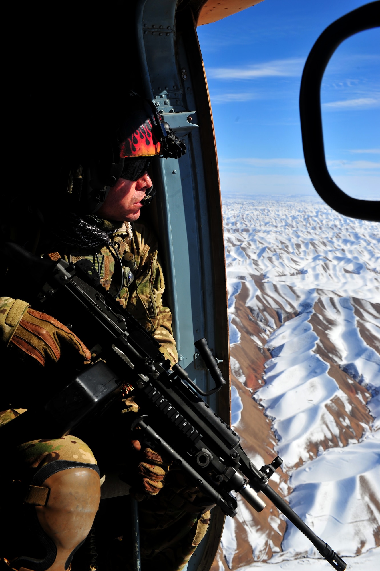 Tech. Sgt. Christian Corella, 838th Air Expeditionary Advisory Group aerial gunner adviser, covers his sector from the door of an Afghan air force Mi-17 helicopter during an emergency resupply flight through western Afghanistan, Nov 11, 2011. The U.S. and Afghan flight crews provided supplies to a remote Afghan Border Patrol outpost. Airmen advise Afghan soldiers on maintenance, operations, flight, and security of the Mi-17 helicopter. Corella is deployed from the 88th Test and Evaluation Squadron at Nellis AFB, Nev., and a native of El Paso, Texas. (U.S. Air Force Photo/Senior Airman Tyler Placie)