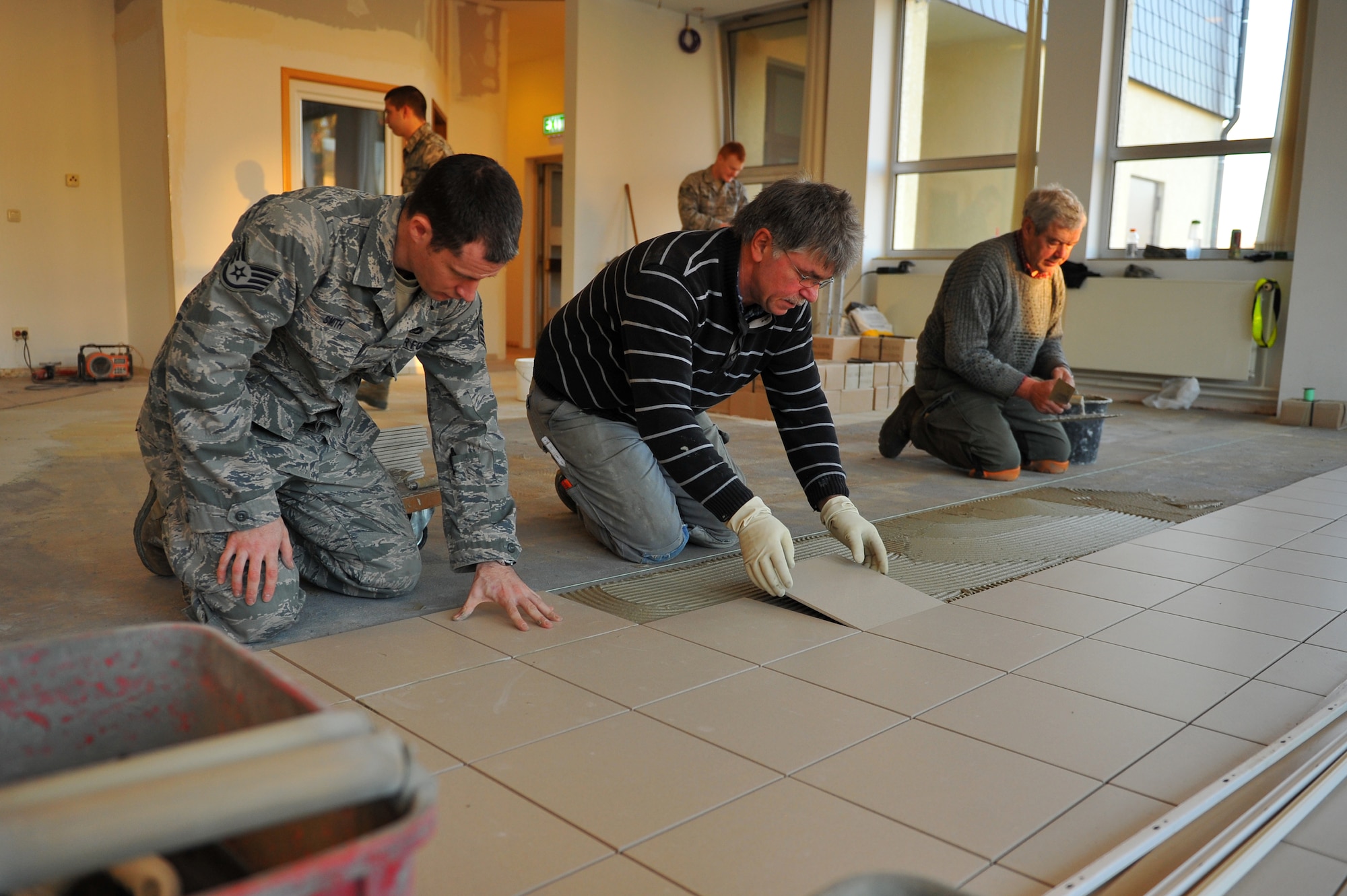 SPANGDAHLEM AIR BASE, Germany – Staff Sgt. Russell Smith and Manfred Blitsch, 52nd Civil Engineer Squadron structures craftsmen, lay tile inside the Mosel Dining Facility here Nov. 16. The 52nd CES is renovating the facility, to include, new flooring, paint, service line and storage facilities. Completion of the facility is scheduled for Jan. 15, 2012. (U.S. Air Force photo/Airman 1st Class Dillon Davis)