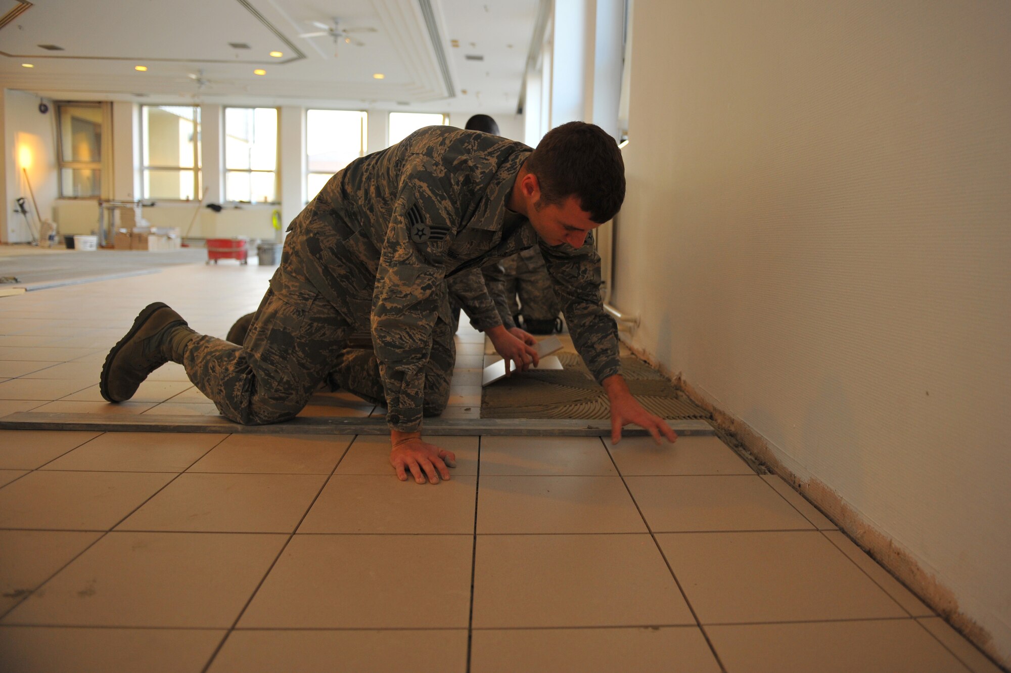 SPANGDAHLEM AIR BASE, Germany – Senior Airman Marshall Browning, 52nd Civil Engineer Squadron structures journeyman, aligns tiles before the adhesive dries inside the Mosel Dining Facility here Nov. 16. The 52nd CES is renovating the facility, to include, new flooring, paint, service line and storage facilities. Completion of the facility is scheduled for Jan. 15, 2012. (U.S. Air Force photo/Airman 1st Class Dillon Davis)