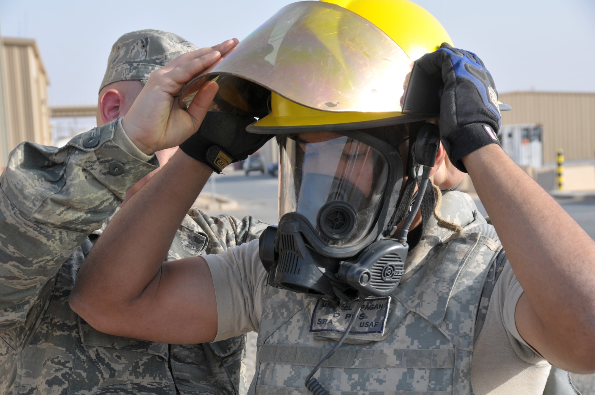 Senior Airman Anthony Hilderbrand helps Senior Airman Michael Pagan get geared up for a firefighter challenge at an undisclosed location in Southwest Asia Nov. 11, 2011. Hilderbrand and Pagan, both 332nd Expeditionary Civil Engineer Squadron firefighters, helped organize the challenge to commemorate Veterans Day. (U.S. Air Force photo by Master Sgt. Paul Mann)