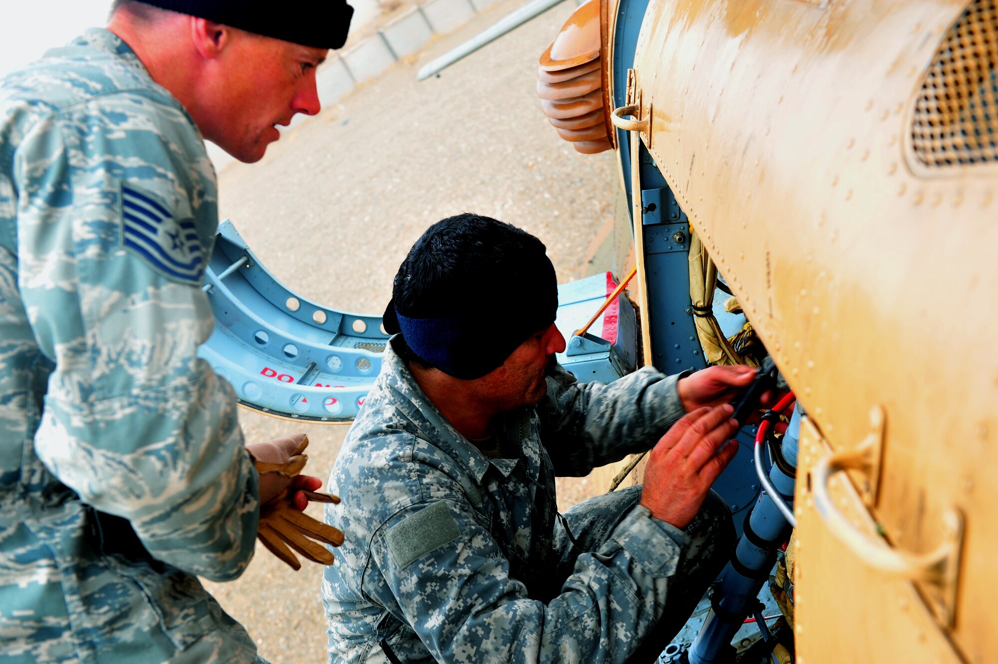 Tech. Sgt. Keith McCarthy,838th Air Expeditionary Advisory Group Detachment 1, maintenance air adviser, looks on as an Afghan maintainer makes sure the Mi-17 helicopter is good to go during preflight checks before a training flight over Herat City, Afghanistan, Nov. 10, 2011. U.S. and Salvadoran airmen advise Afghan soldiers on maintenance, operations, and security of the Mi-17 helicopter. McCarthy is deployed from the 723th Aircraft Maintenance Sq. at Moody AFB, Ga. (U.S. Air Force Photo/SrA Tyler Placie)