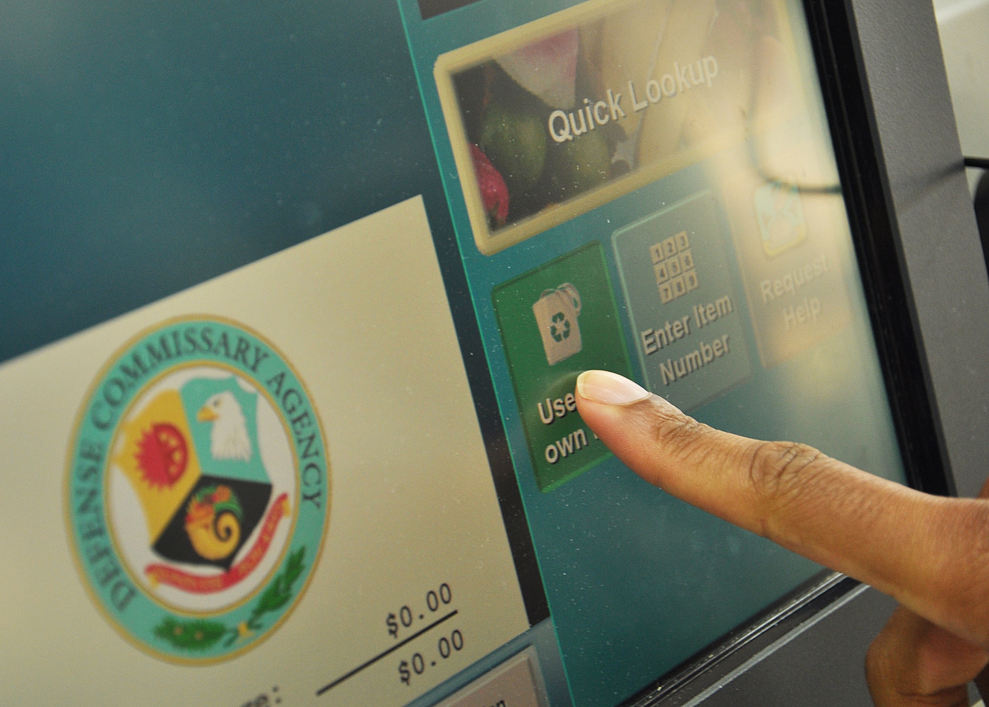 SPANGDAHLEM AIR BASE, Germany – Staff Sgt. Idris Royal, 52nd Force Support Squadron, pushes a button on a commissary self-service checkout machine here Nov. 15 to allow the use of a personal, re-usable bag for grocery storage. The 52nd Fighter Wing’s foreign object damage manager, in collaboration with base civilian agencies, provided re-usable grocery bags to Airmen and their families at the commissary in an effort to enhance recognition of the dangers loose debris have on the base’s flying mission. (U.S. Air Force photo/Staff Sgt. Daryl Knee)