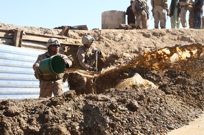 Cpl. Samuel Escutia Jr., a combat engineer with Alpha Company, Combat Logistics Battalion 1 and 21-year-old native of Reedley, Calif., empties water from a culvert here, Nov. 12. Marines of Alpha Co. are currently repairing the support structure on a bridge located at a major intersection that connects Marjah and Nawa districts. The bridge receives heavy foot and vehicle traffic due to the local bazaar, as well as Afghan and coalition military convoys.