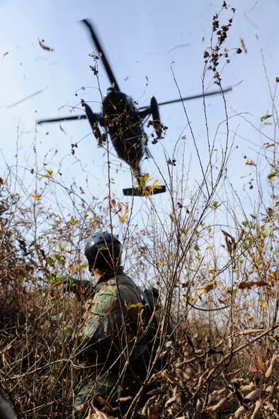 1st Lt. Stephen Cecil, 80th Fighter Squadron F-16 pilot, takes cover as a Republic of Korea's HH-60 helicopter arrives at his designated zone to pick him up during a Peninsula-wide Operational Readiness Exercise in Jeongan-myeon, Republic of Korea, on Nov. 16, 2011.  Cecil simulated a downed pilot in his scenario. His scenario was one of the many during the PENORE to prepare the Wolf Pack for wartime contingencies and their operational readiness inspection. (U.S. Air Force photo by Staff Sgt. Rasheen Douglas/Released)