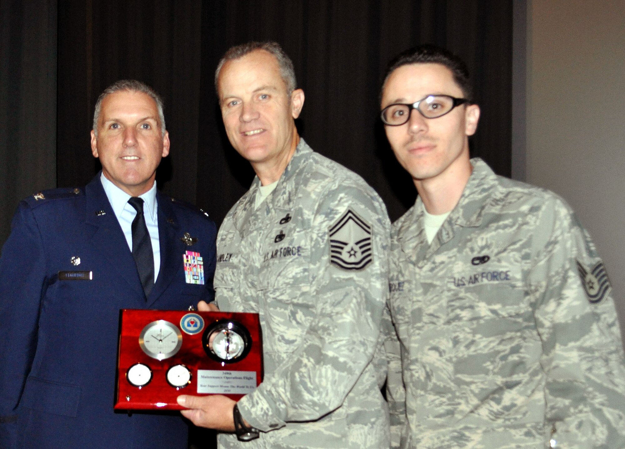 TRAVIS AIR FORCE BASE, Calif. -- At Commander's Call Oct. 23, Col. Jay Flournoy, wing commander, presented a gift to the 349th Maintenance Operations Flight, from the Travis Fisher House. Accepting the gift are left, Senior Master Sgt. James Standley and Tech. Sgt. Anthony Marquez, 349th MOF Booster Club president. (U.S. Air Force photo/Senior Master Sgt. Ellen Hatfield)  