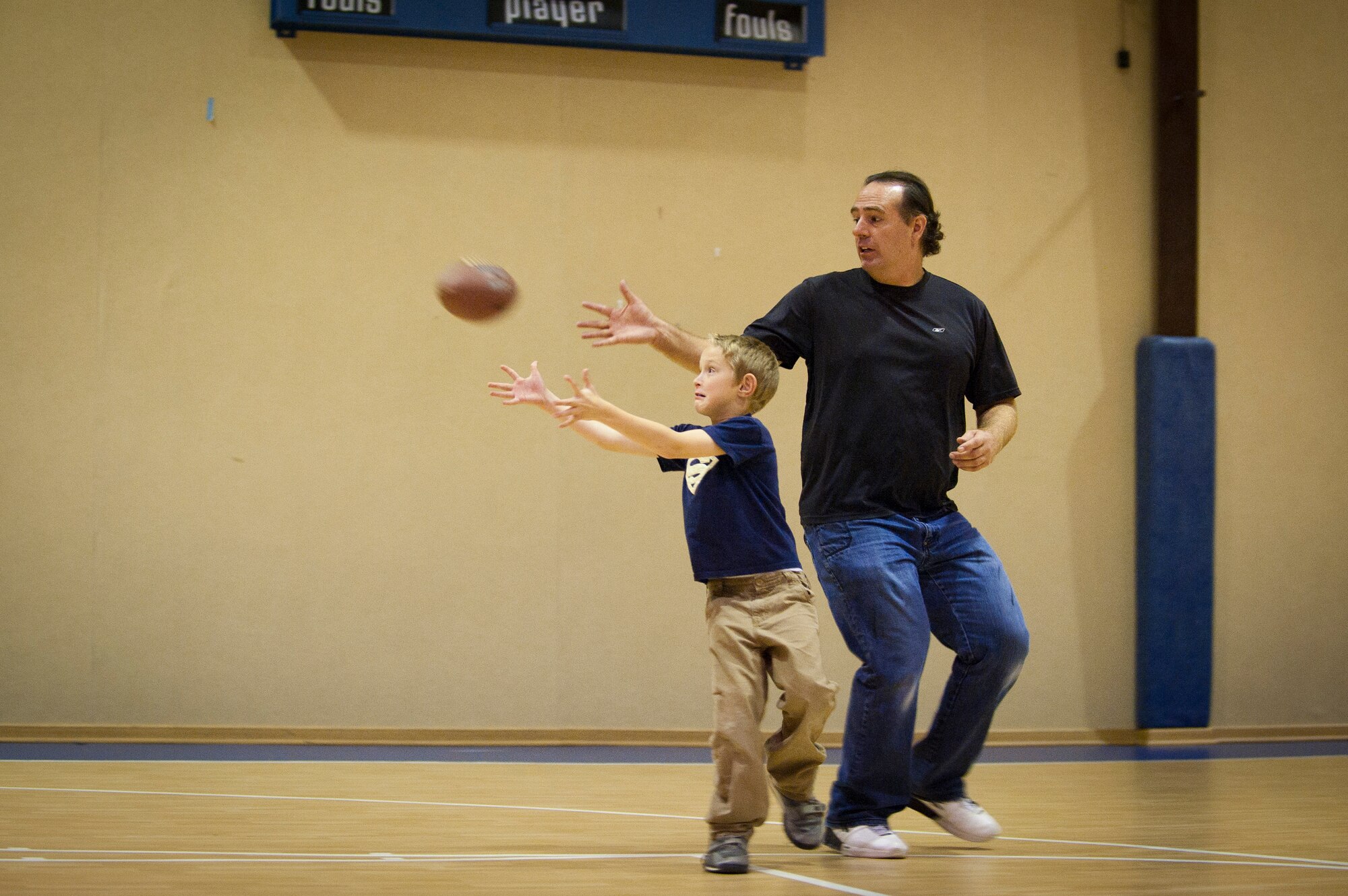 A child reaches for a pass with the help of Marcus Grothues, 39th Force Support Squadron youth program specialist, during a football mini-camp Nov. 16, 2011, at Incirlik Air Base, Turkey. The camp, hosted by the youth center, was held Nov. 14-18 in lieu of the youth football season and featured instruction on a variety of techniques for beginning players. (U.S. Air Force photo by Tech. Sgt. Michael B. Keller)