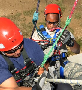 Randy Simeon and Airman 1st Class Perry Robinson, 902nd Civil Engineering fire services, work together during a training class Nov. 16, in high angle and confined space training. Robinson assists Simeon into a hoist to be lowered to the ground. (U.S. Air Force Photo by Don Lindsey)