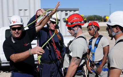 Jimmy Sibley (left), Wright Rescue Solutions Inc., instructs Joint Base San Antonio-Randolph and Universal City, Texas fire fighters in the correct way to hook up rigging when performing a high angle and confined space rescue Nov. 16 through the high angle/confined space technician course. The training scenario's gamut ranges from higher-altitude tower and multistoried building window rescues to confined space rescues such as around telecomunication lines and a water tower. (U.S. Air Force Photo by Don Lindsey)