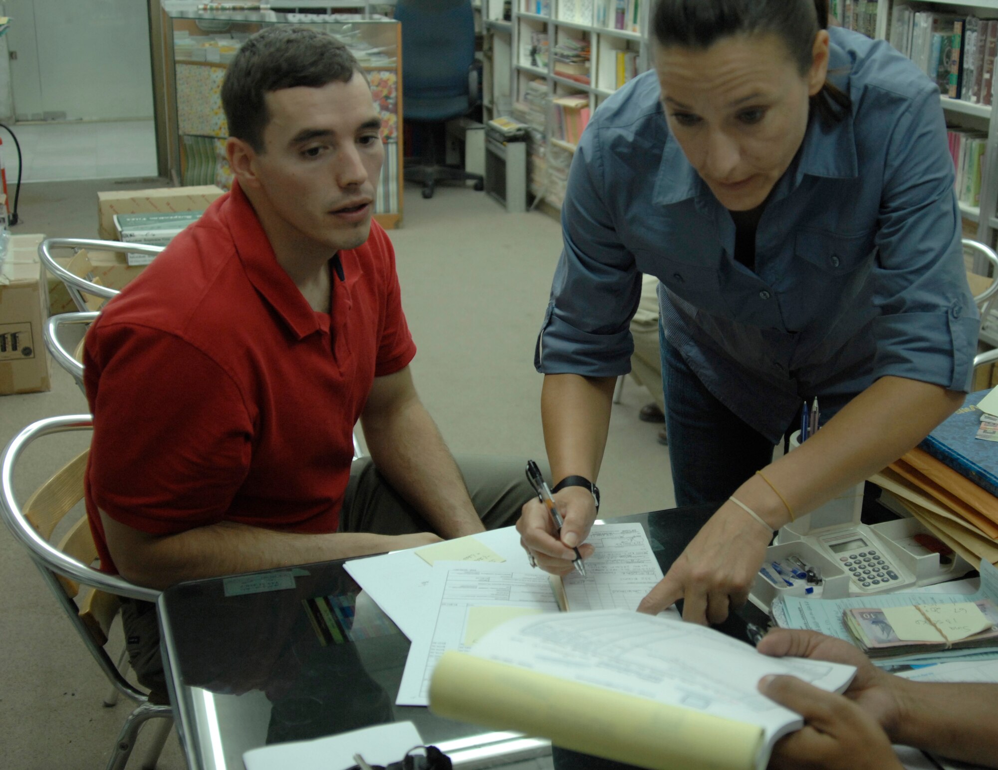 First Lt. Anthony Schelstrate, 332nd Expeditionary Contracting Squadron contracting officer, and Master Sgt. Julianna Gibson, 332nd Air Expeditionary Wing Financial Management disbursing agent, make a payment and sign contracts with a local vendor at an undisclosed location in Southwest Asia Nov. 14, 2011. The finance and contracting Airmen work to purchase items and services needed for the 332nd AEW while building partnerships with host nation vendors. Schelstrate is deployed from Laughlin Air Force Base, Texas, and is a native of Phoenix, Ariz. Gibson is deployed from Pope Air Force Base, N.C., and is a native of Greenville, Texas. (U.S. Air Force photo by Senior Airman Amber R. Kelly-Herard) 