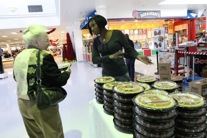 Jessica Ross, a department support trainer with Marine Corps Family Team Building gave away pumpkin pies at the Marine Corps Main Exchange aboard Marine Corps Base Camp Lejeune, Nov. 19. More than 11,000 pies, which were stacked high in the back of a semi truck tractor trailer, were provided by an Eastern United States grocery chain.::r::::n::