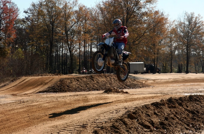 A Marine with the 2nd Marine Logistics Group rides over a jump during the off-road quarterly ride at Busco Beach in Goldsboro, N.C., November 18, 2011. The intent of the training was to facilitate off-road training for Marines and sailors with the 2nd MLG. The training was given by more experienced riders who possessed the knowledge junior riders could benefit from. (U.S. Marine Corps photo by Pfc. Franklin E. Mercado)